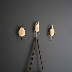 three bugs mounted to the side of a gray wall next to a pair of purses