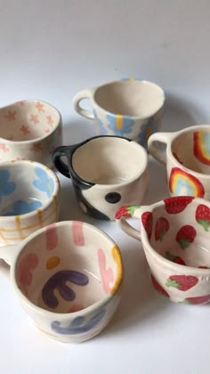 six cups with different designs on them are sitting next to each other and one has a spoon in it