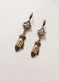 ■ Antique Victorian style earrings. These earrings are inspired by the traditional Victorian design, but they are also very reminiscent of palmistry. The hand is a common symbol and is used as an amulet of protection and blessing. -The earrings are approximately 2.3622 inches long. The product is handmade with great care. ♡ In my shop there are many handmade jewels for all tastes, come and look at them you are welcome! ♡ Hand Cast Brass Dangle Jewelry, Symbolic Bronze Brass Earrings, Antique Brass Jewelry With Lever Back Ear Wires, Hand-cast Brass Dangle Earrings, Symbolic Bronze Drop Earrings, Bronze Copper Jewelry With Lever Back Ear Wires, Vintage Hand Cast Metal Earrings, Victorian Style Earrings, Gothic Accessories