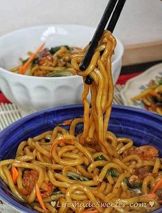 noodles being lifted from a bowl with chopsticks