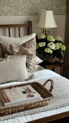 a bed topped with pillows next to a basket filled with flowers on top of it