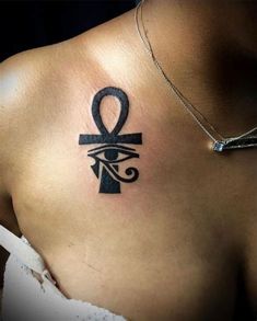 an egyptian symbol tattoo on the back of a woman's shoulder and chest,