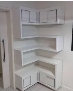 an empty corner in the middle of a room with white shelves and cupboards on each side