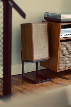 an old fashioned radio sitting on top of a wooden stand with wicker baskets next to it