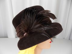 "Vintage cloche style hat in brown felted wool embellished with wide velveteen hatband and feathers. Very good vintage condition. Label: Laura Ashley Crown height 4 1/2\" Inside brim 22\" We have many hats listed in our store. Check them out here: https://www.etsy.com/shop/ofcorsetsvintage?section_id=14391072&ref=shopsection_leftnav_7 But why just limit yourself to one? We offer discount shipping when purchasing multiple items and international shipping. Please email me for a quote." Winter Felt Hat With Feathers And Short Brim, Winter Felt Hat With Wide Brim And Feathers, Brown Fur Felt Top Hat For Formal Occasions, Formal Brown Top Hat For Fall, Brown Wide Brim Felt Hat For Party, Vintage Wide Brim Mini Hat For Fall, Vintage Brimmed Costume Hats For Fall, Vintage Costume Hats With Short Brim For Fall, Brown Fedora With Feathers For Kentucky Derby