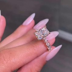 a woman's hand holding an engagement ring with three stones on the band and one stone in the middle