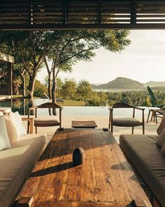 a wooden table sitting in the middle of a living room next to a large window