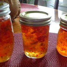 three jars filled with food sitting on top of a red place mat next to each other