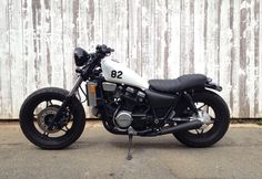 a black and white motorcycle parked in front of a wooden fence