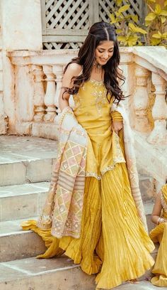 two women in yellow dresses are standing on steps and one is wearing a white shawl