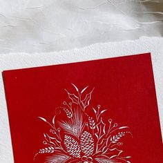 a red and white christmas card with pinecones on the front, surrounded by snowflakes