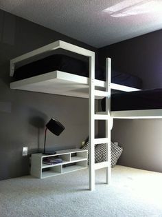 a bunk bed sitting in the middle of a bedroom next to a desk and lamp