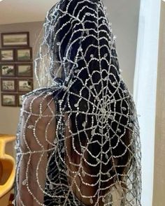 the back of a woman's head with beads on her hair and veil over it