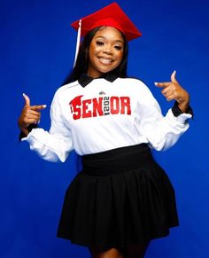 a woman in a graduation cap and gown posing for a photo with her hands up