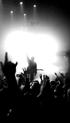 a man standing on top of a stage with his arms in the air while holding a guitar