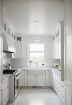 an all white kitchen with lots of counter space and cupboards on the wall, along with a window