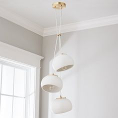 three lights hanging from the ceiling in a room with white walls and wood flooring