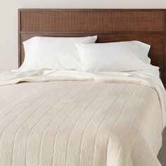 a bed with white pillows and blankets on top of it, in a bedroom setting