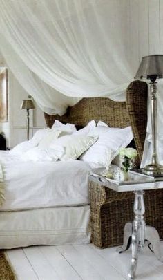 a bedroom with white bedding and wicker furniture