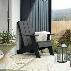 a black chair sitting on top of a porch next to a potted plant