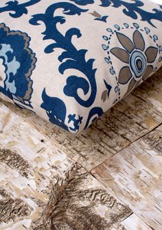 a blue and white pillow sitting on top of a wooden floor next to a piece of wood