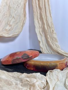 two wooden bowls sitting on top of a table next to a drape covered curtain