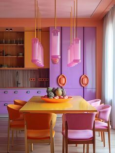 a dining room with purple walls and orange chairs around a yellow table surrounded by pink cabinets