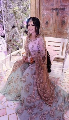 a woman sitting on top of a white bench wearing a blue and pink dress with flowers