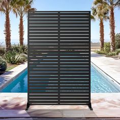 an outdoor pool area with palm trees and a privacy screen on the side of it