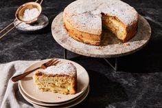 a cake on a plate with a slice taken out of it and two plates next to it