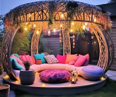 an outdoor seating area with lots of pillows and lights