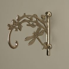 a metal hook with dragonflys and flowers attached to the handle on a wall