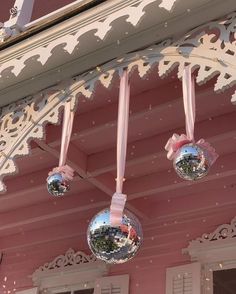 three mirrored balls hanging from the side of a pink house