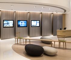 an office lobby with three televisions on the wall and two tables in front of them