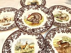 four plates with animals painted on them sitting on a table