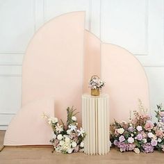 an assortment of flowers are on display in front of a pink sculpture and white background