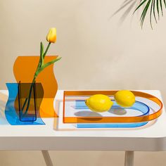 two lemons are sitting on a table next to a vase with yellow tulips