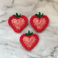 three crocheted strawberries sitting on top of a marble counter