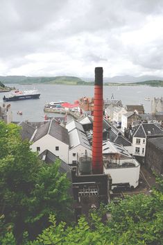 an industrial area with buildings and a boat in the water behind it on a cloudy day