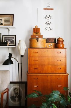 a living room filled with furniture and pictures on the wall next to a plant in front of a window