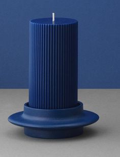 a blue candle holder sitting on top of a gray table next to a white wall