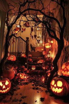 pumpkins lit up on the ground in front of an entry way with stairs and trees