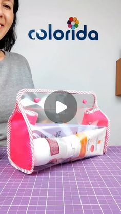 a woman sitting in front of a pink bag filled with cosmetics and toothpaste