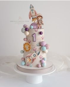 a three tiered cake decorated with an astronaut and rocket on it's side