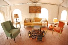 a living room filled with lots of furniture under a large white canvas tent covered in windows