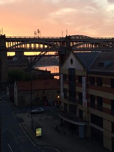 the sun is setting over an old city with a bridge in the backgroud