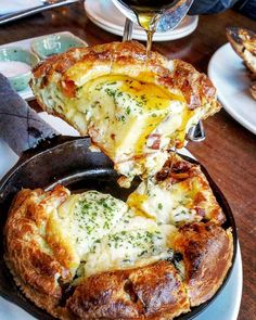 a person is pouring cheese into a bread dish