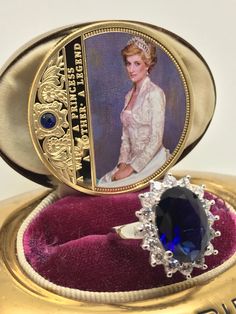 an oval shaped ring with a blue stone in the center, on top of a purple velvet case