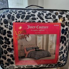 a piece of luggage sitting on top of a bed covered in animal print sheets and pillows