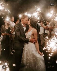 a bride and groom kissing while surrounded by sparklers